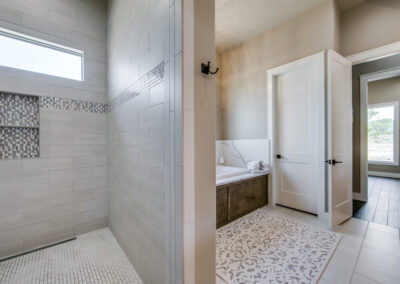 Soaking tub and walk-in shower in master suite of custom Texas home.